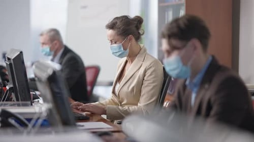 Professional Female Manager in Covid19 Face Mask Typing on Computer Keyboard in Office with