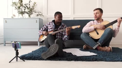 Two Young Men Playing Guitars Together Indoors