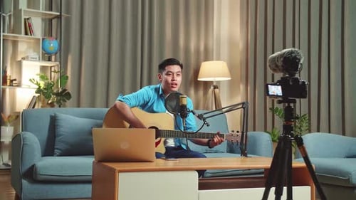 Asian Man Playing Guitar And Sing A Song While Live Streaming For His Social Media Channel