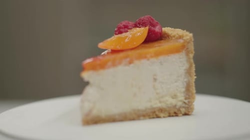 Slice of Fruit Topped Cheesecake Rotating on White Plate