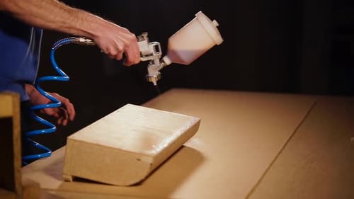 Der Mensch besprüht Holz mit speziellem Flüssigkleber