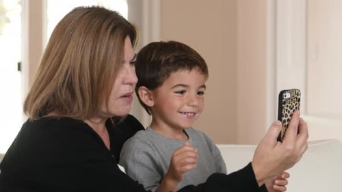 Woman and Boy Looking at Phone Together Indoors