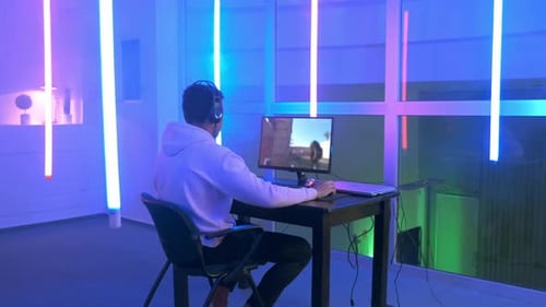 Young Adult Plays Video Game in Neon Room