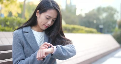 Woman Using Smartwatch in City Park