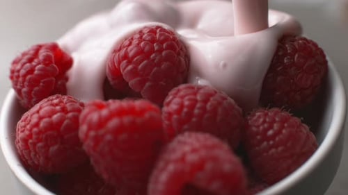 Pink Yogurt Poured Over Bowl of Red Raspberries