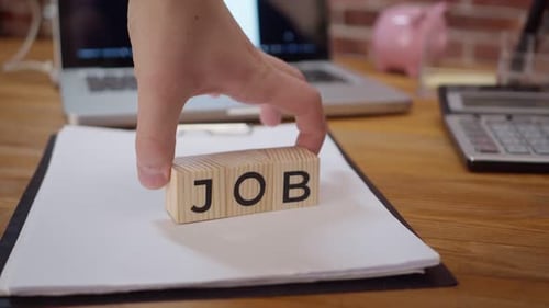 Holzwürfel mit der Aufschrift „New Job“ werden auf den Schreibtisch gelegt