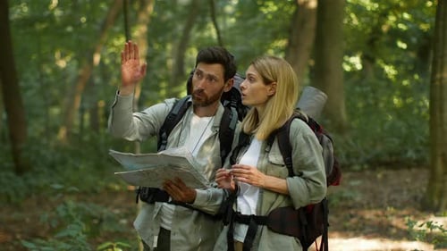 Couple of Active Middle Aged Tourists Using Paper Map to Find Right Route Discussing Way During