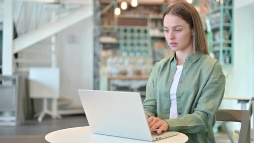 Tired Woman with Laptop Having Neck Pain in Cafe