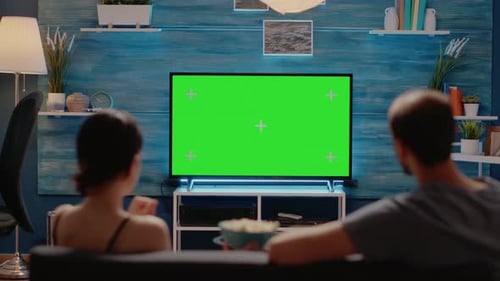 Joven y mujer viendo la pantalla verde en la pantalla de la televisión