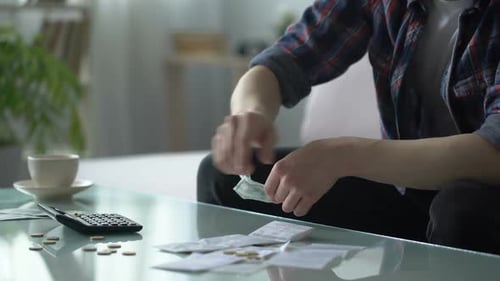 Poor Man Calculating Expenses, Having Few Dollars and Cents on Table, Debts