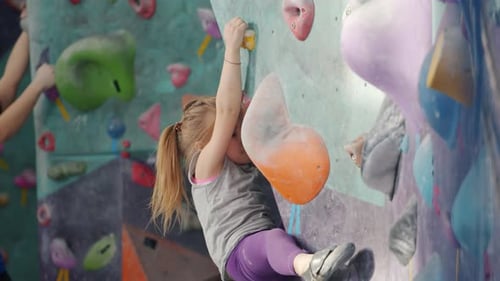 Serious Kid Concentrated on Rock-climbing in Indoor Facility Moving Up Wall