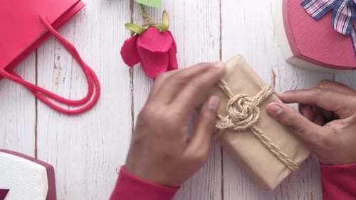 Top View of Man's Hand Holding a Gift Box on Table