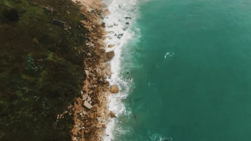 Aerial Motion From Rocky Coastline Hill Across Beach To Town