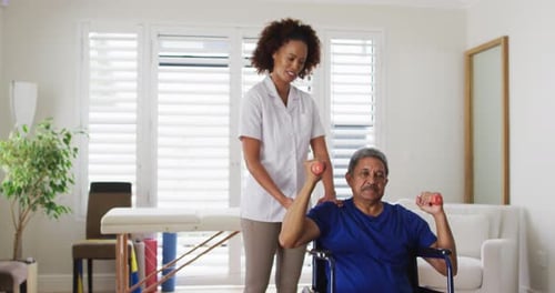 Therapist Assisting Senior Man Lifting Weights in Wheelchair