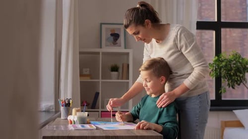 Woman Helps Child Create Art With Paint Brushes