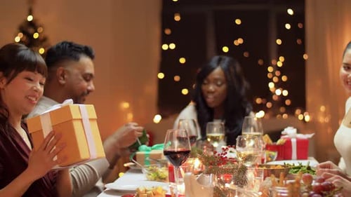 Friends Exchanging Festive Christmas Gifts at Dinner Table