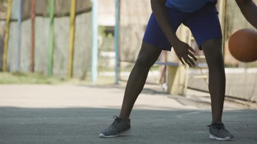 Young Adult Dribbling Basketball on Outdoor Court