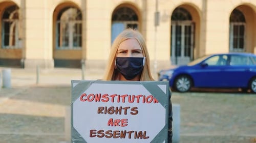 Marche de protestation : une femme masquée défend la protection des droits constitutionnels
