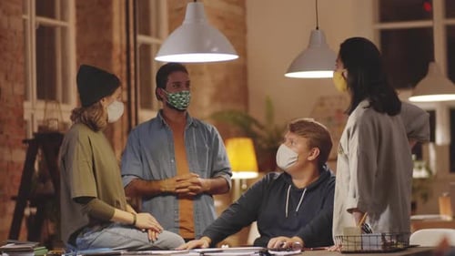 Young Colleagues in Protective Masks Working in Team in Loft Office