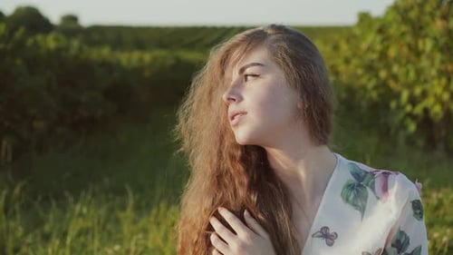 Woman with auburn hair in grassy field