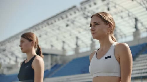 Female Runners at Athletics Track Crouching at the Starting Blocks Before a Race. In Slow Motion