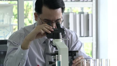 Adult Man Inspecting Specimen with Microscope