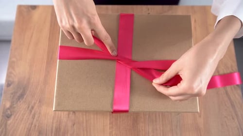 Hands Tie Pink Ribbon on Gift for Celebration