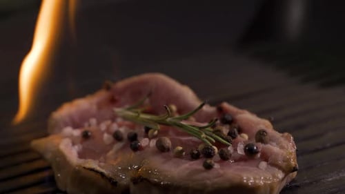 Seasoned Steak Cooking on a Grill with Flames