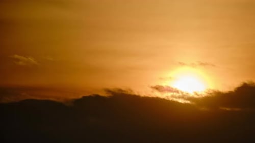 Evening dramatic sky with clouds during sunset, timelapse. The sun sets behind dark clouds