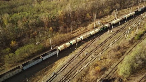 Aerial View of Freight Train Riding in Countryside. Bird's Eye View of Railroad Station Near Forest