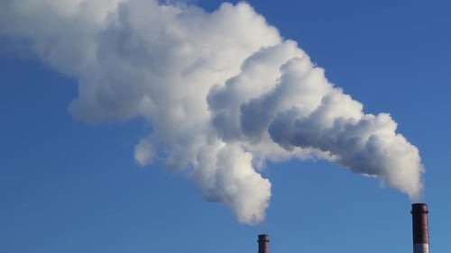 Weißer Rauch kommt aus zwei Röhren gegen den blauen Himmel, Zeitraffer