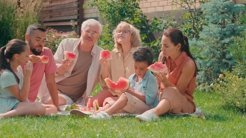 Family Enjoys Watermelon Picnic in Summer Backyard