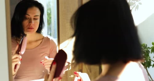 Woman Brushing Hair in Mirror at Home