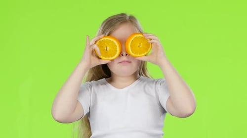 Little Girl Holding an Orange Slice Closes Her Eyes and Curves. Green Screen