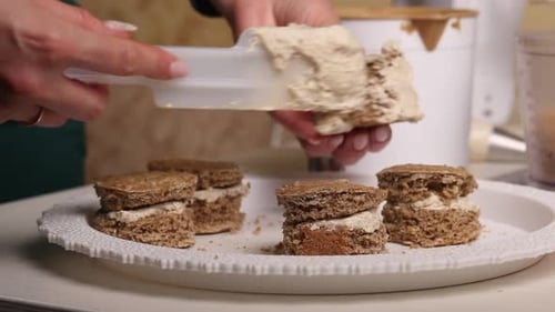A Woman Makes A Biscuit Cake. Applies Butter Cream To The Workpieces. Close Up.