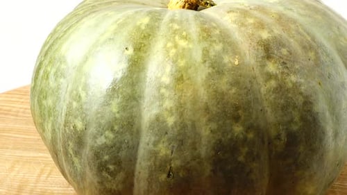 Green Pumpkin Rotating on Wooden Surface