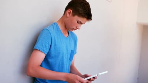 Attentive schoolboy using digital tablet