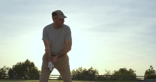 Man Swinging Golf Club at Sunrise or Sunset