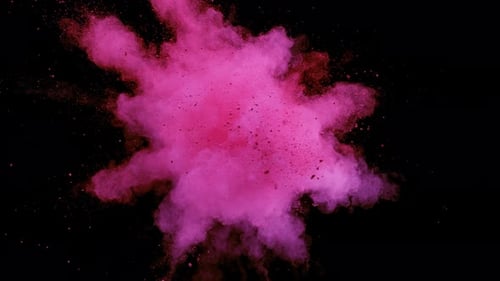 Buntes Pulver/Partikel fliegen, nachdem sie vor schwarzem Hintergrund explodiert wurden. Zeitlupe.