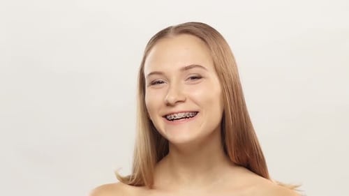 Niña con soportes en los dientes, reloj y parpadeo.
blanco