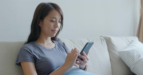 Woman Relaxing at Home Using Smartphone