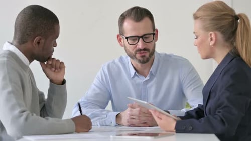 Empresario mestizo conversando mientras usa la tableta y toma notas