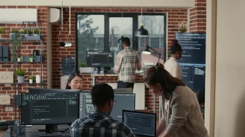 Two Software Developers Doing High Five Hand Gesture at Desk with Multiple Screens Running Ai Code