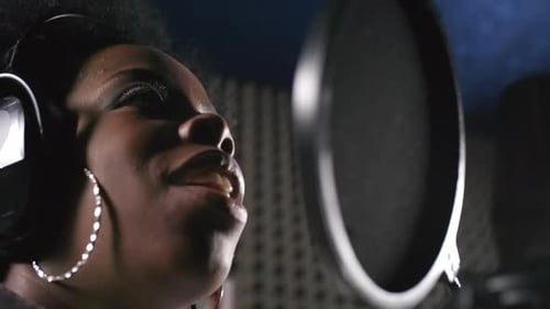 Young Woman Singing into Microphone in Recording Studio