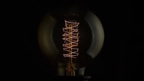 Glowing Filament Lightbulb Against Black Background