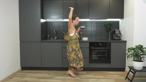 Woman Dancing Joyfully in Modern Kitchen with Coffee