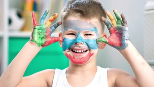 Happy Child with Colorful Paint on Face and Hands