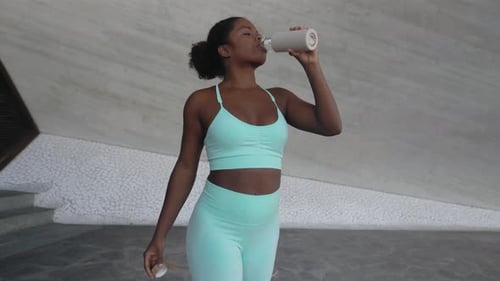 Woman Drinking Water After Workout in Urban Area