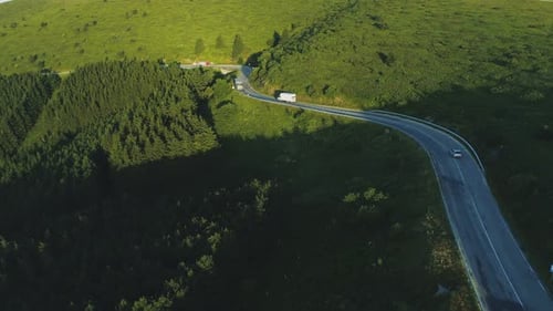 Cargo Truck and Car Driving on a Winding Road in the Hills Top View