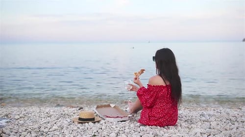 Woman Having a Picnic with Pizza on the Beach